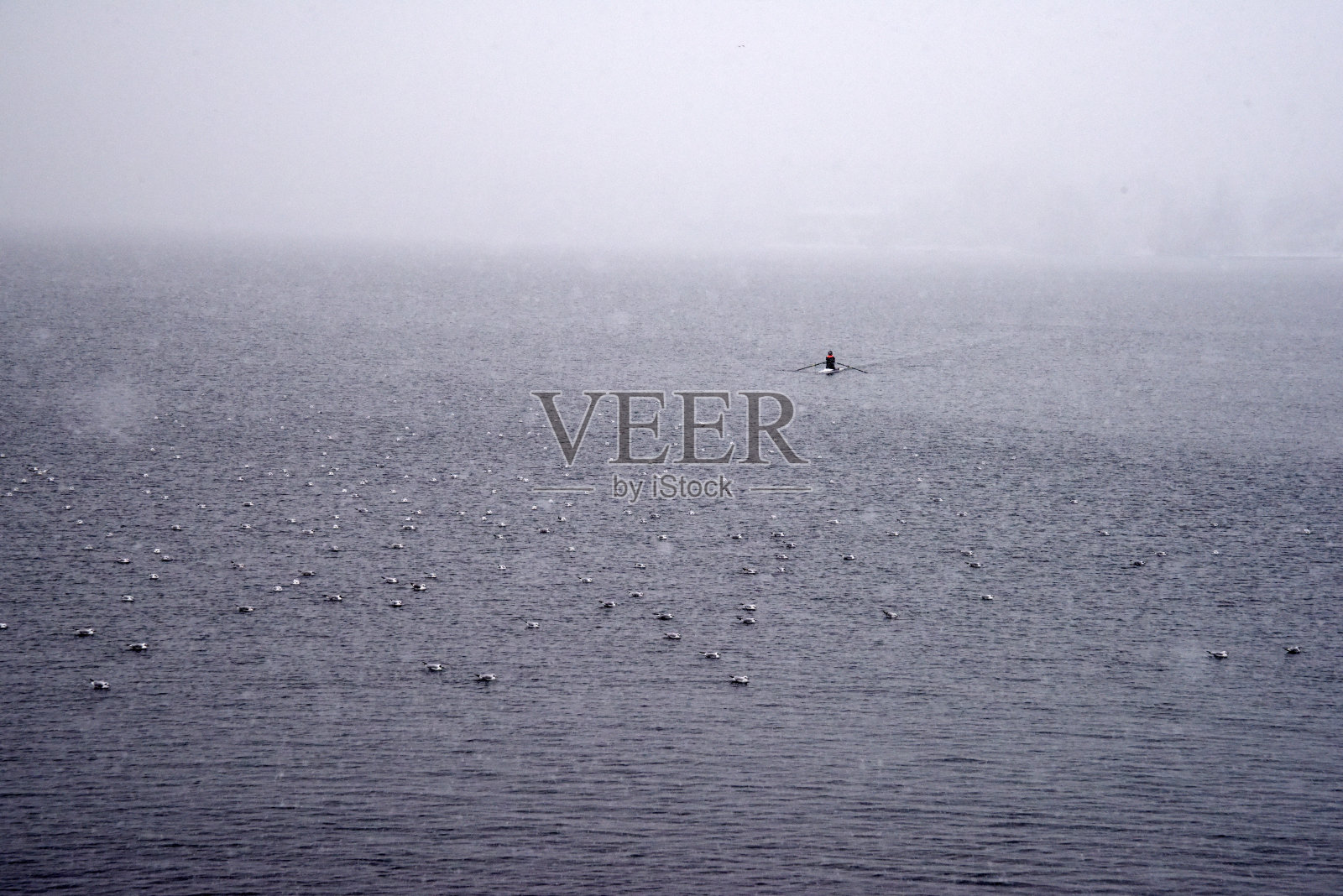 下雪时湖面上的船夫照片摄影图片