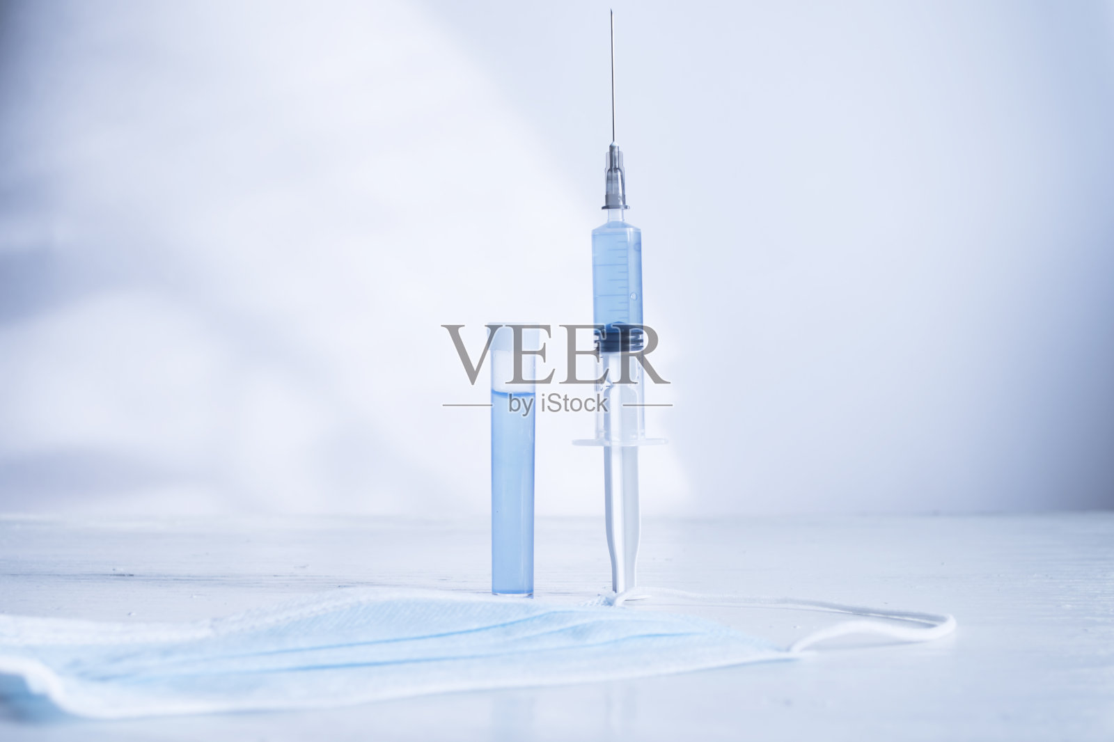 蓝色背景上的注射器和药瓶。照片摄影图片