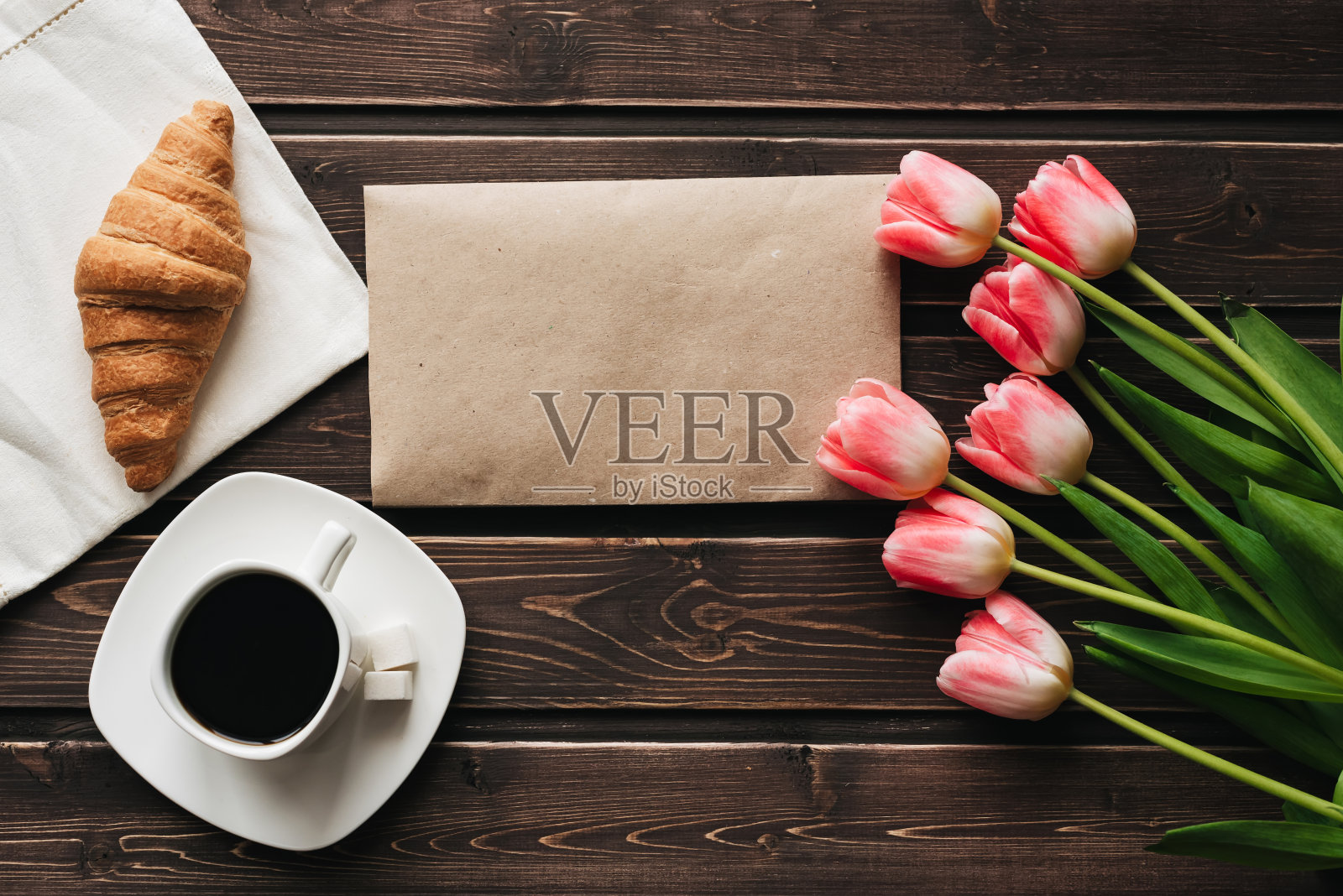 一杯咖啡，一束粉红色的郁金香花和一个羊角面包作为早餐照片摄影图片