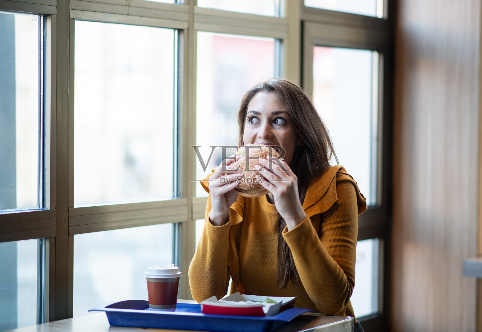 年轻女子在吃汉堡。照片摄影图片