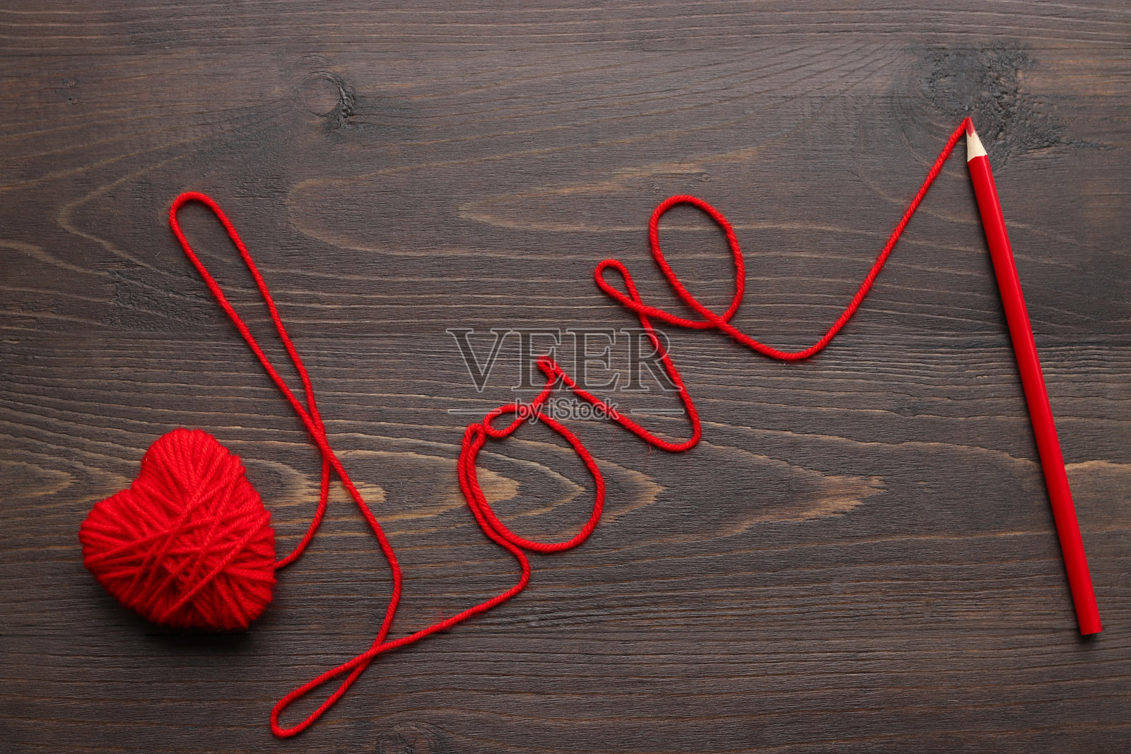 用红线织成的心，上面刻有“爱”字和一支铅笔照片摄影图片