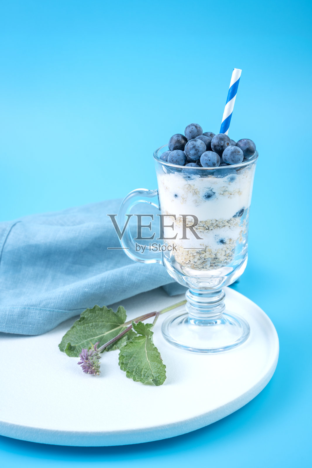 浆果，坚果，奶油在一个透明的玻璃上，在柔和的蓝色背景照片摄影图片