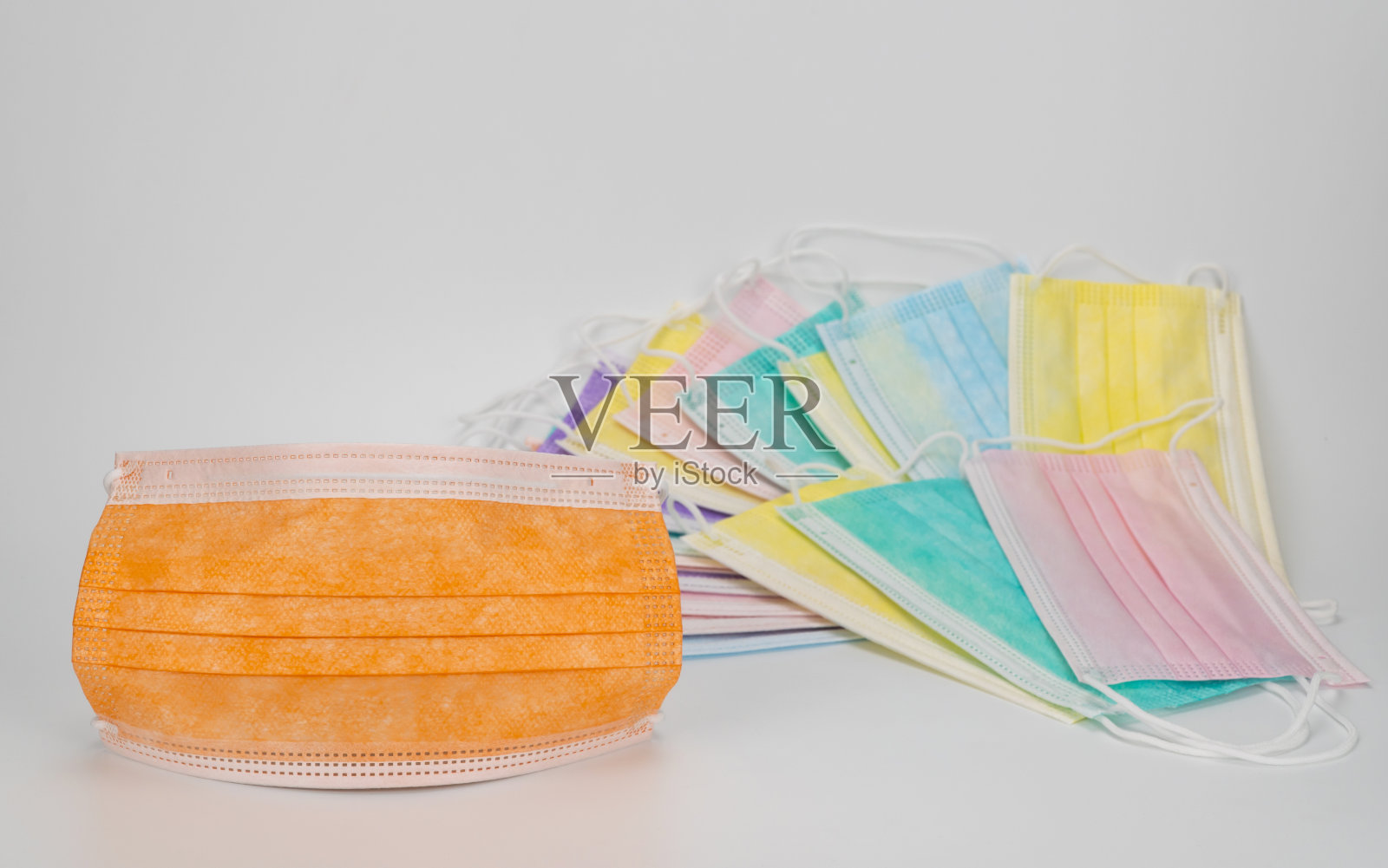 迷人的橙色外科防护口罩和彩色口罩。白色背景上的医用呼吸绷带。预防冠状病毒的彩色抗病毒口罩。照片摄影图片