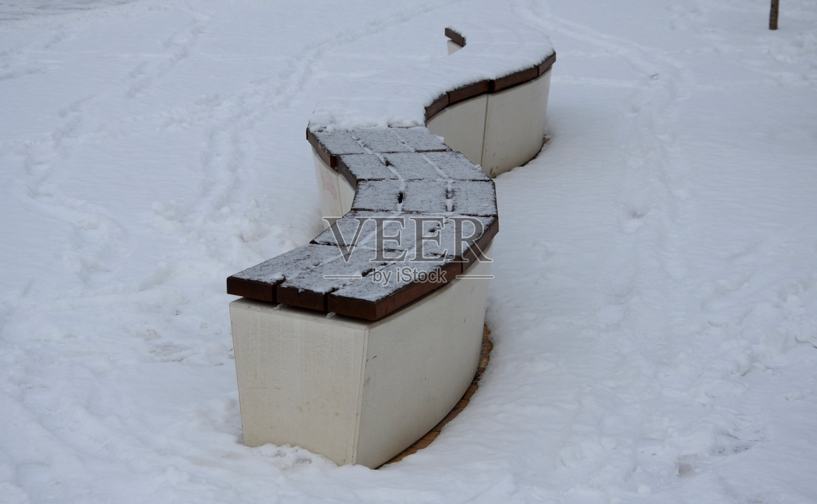 混凝土白色的公园长椅造型在冰雪广场上，混凝土表面干净光滑。有些长椅有木镶板，呈波浪状，彼此垂直照片摄影图片