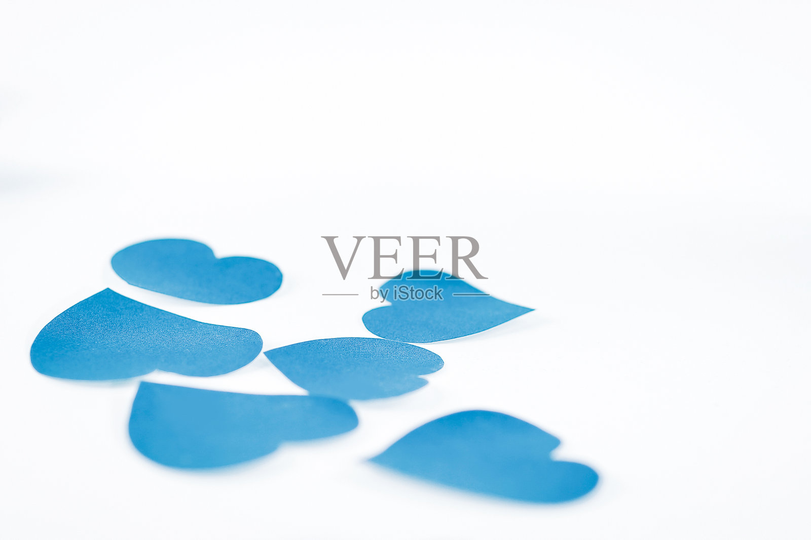 蓝色的心和粉红色的花瓣在白色的背景上。照片与复制照片摄影图片