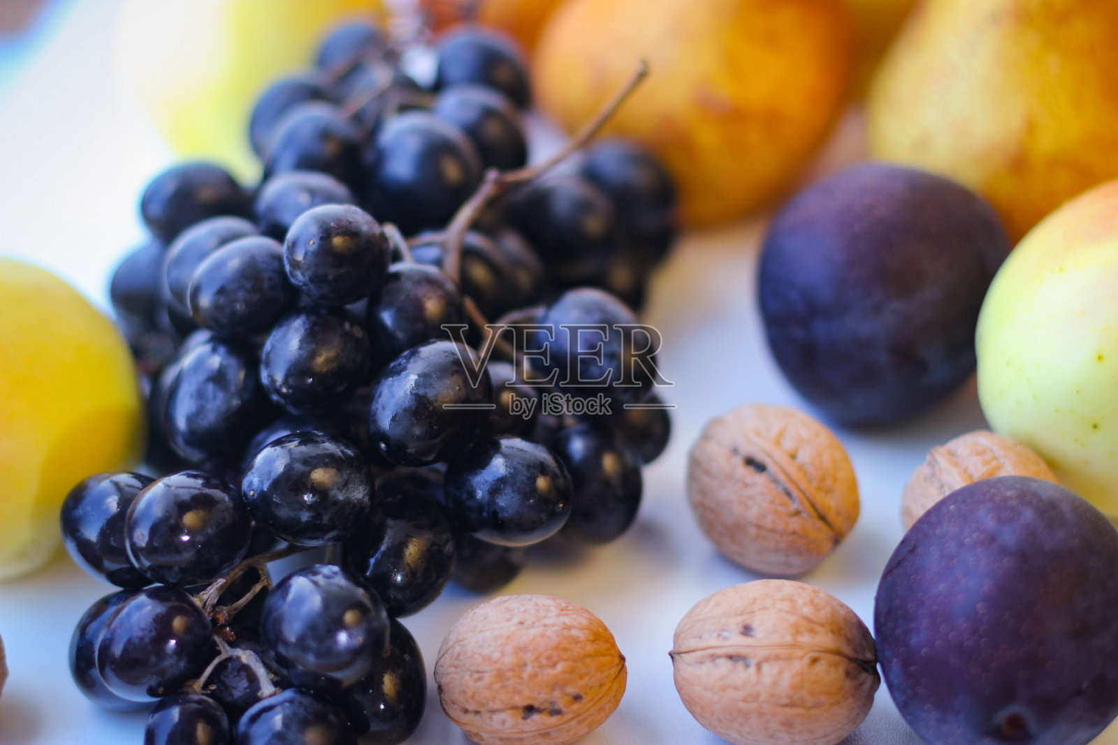 成熟的秋天的果实站在一起，创造一个静物。黑葡萄、李子、梨和苹果。照片摄影图片