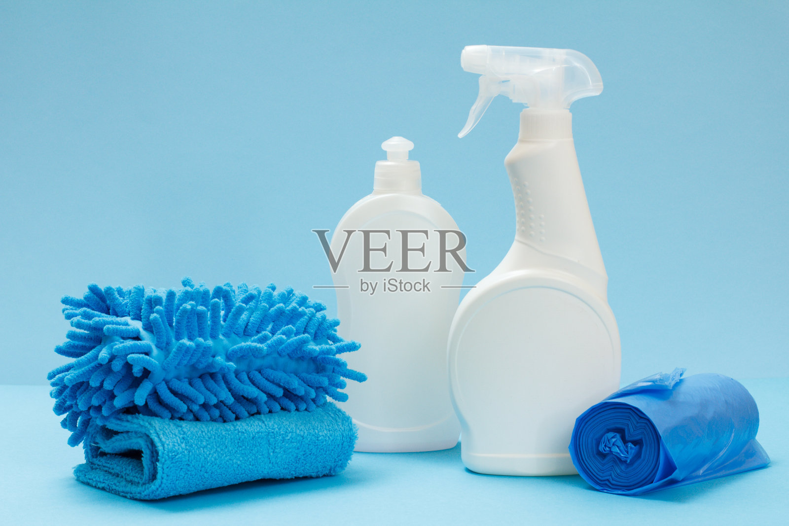 蓝色背景上的洗涤剂，抹布和海绵。照片摄影图片