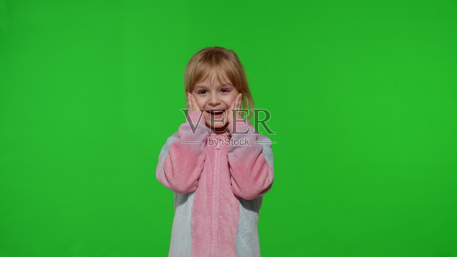 惊奇的小女孩穿着独角兽服装睡衣显示哇反应，完美的惊喜照片摄影图片