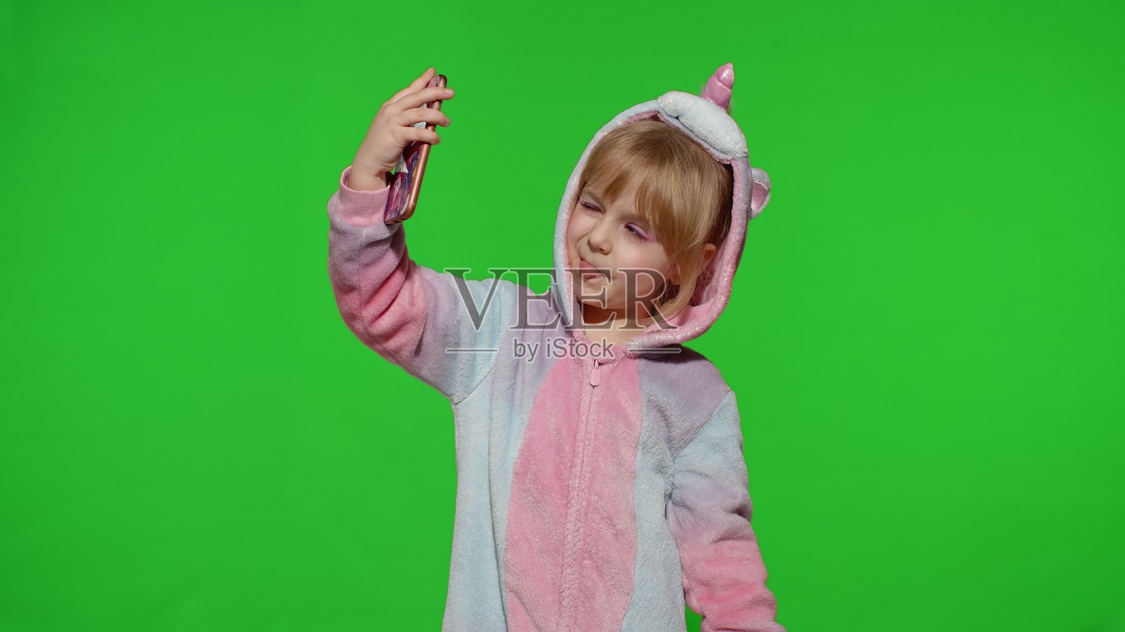 孩子女孩穿着独角兽服装睡衣使用智能手机，孩子情绪化地在手机上自拍照片摄影图片