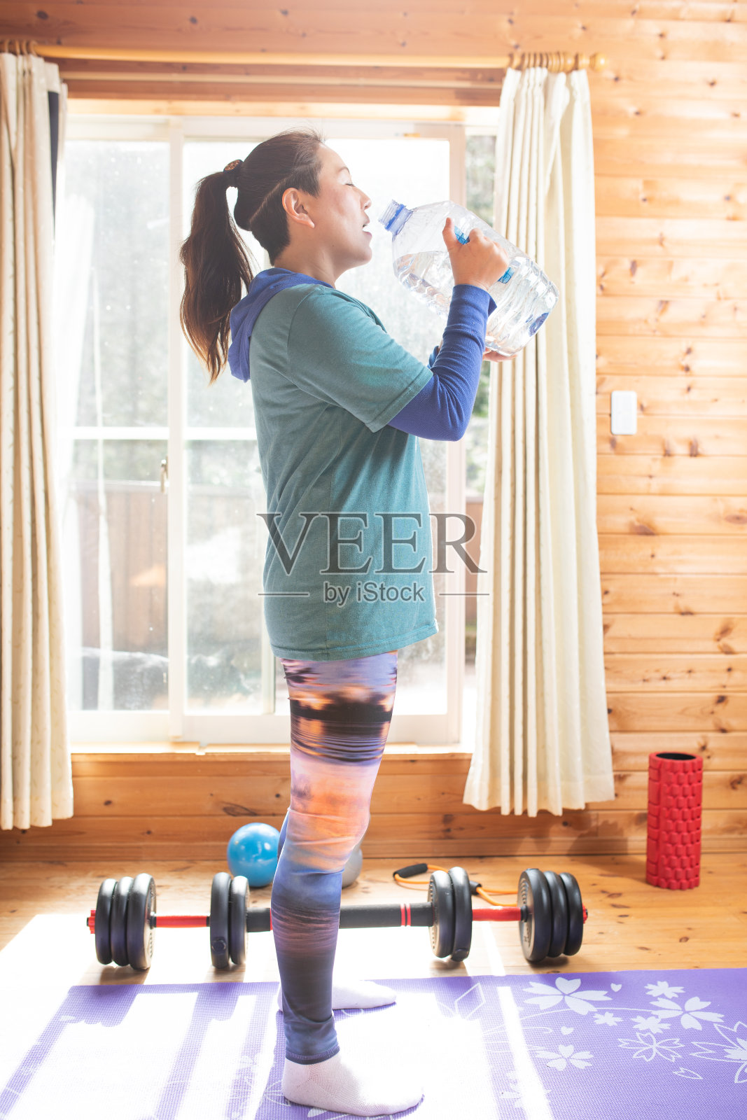 一个女人在锻炼的间隙喝了一个大瓶子里的水照片摄影图片