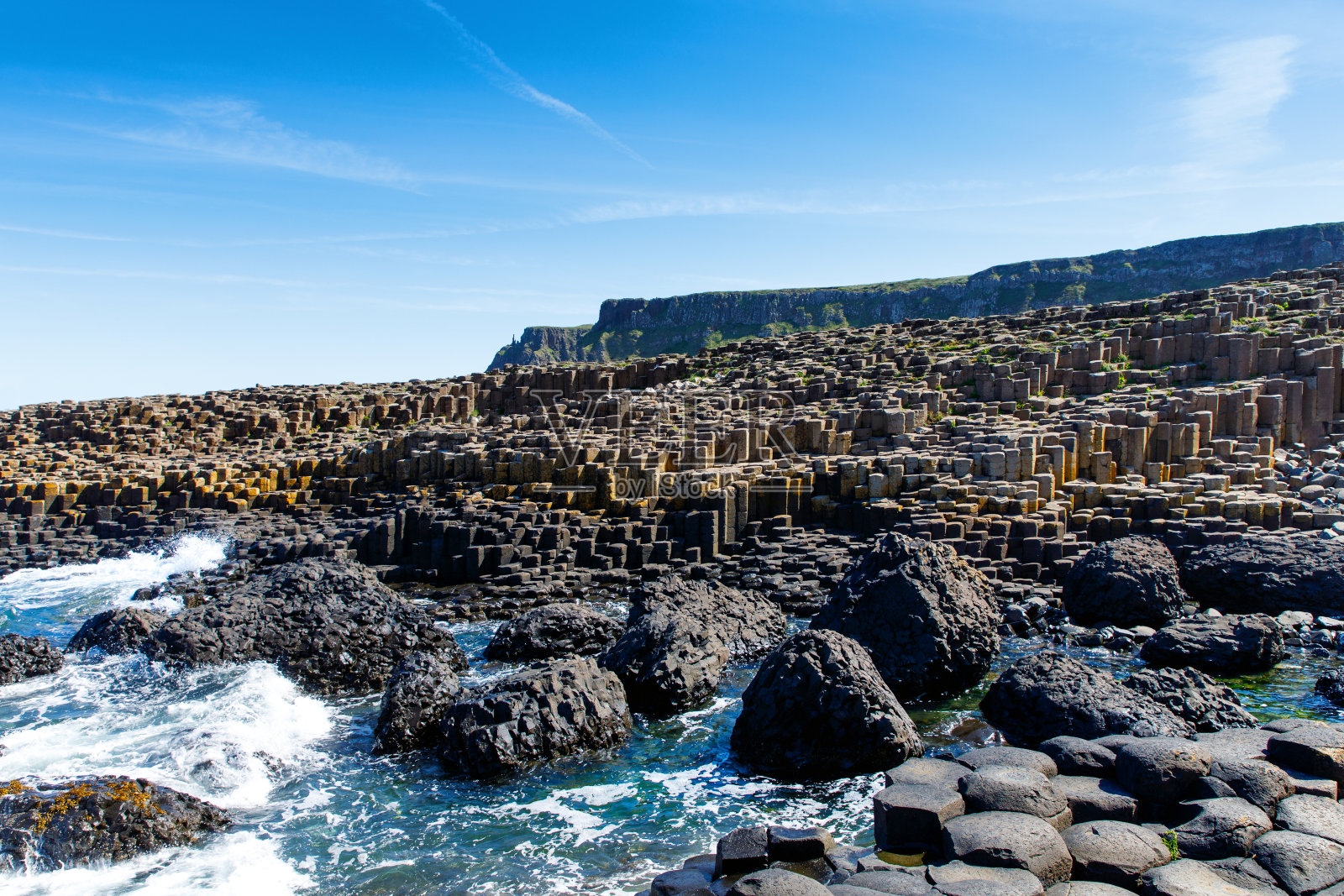 在北爱尔兰安特里姆郡，夏季的蓝天下，巨人堤道的风景。联合国教科文组织的遗产。这是一个由玄武岩柱组成的区域，是古代火山裂缝喷发的结果照片摄影图片