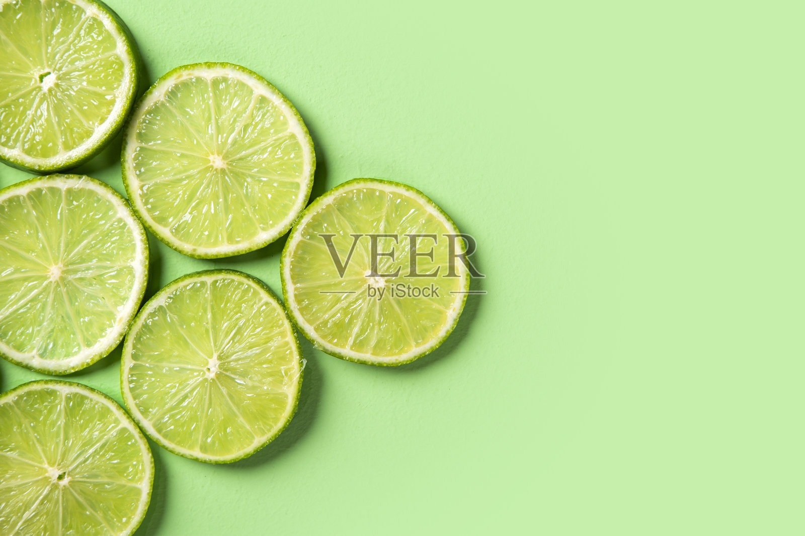 一片新鲜多汁的绿色柠檬。绿色背景,模式。照片摄影图片