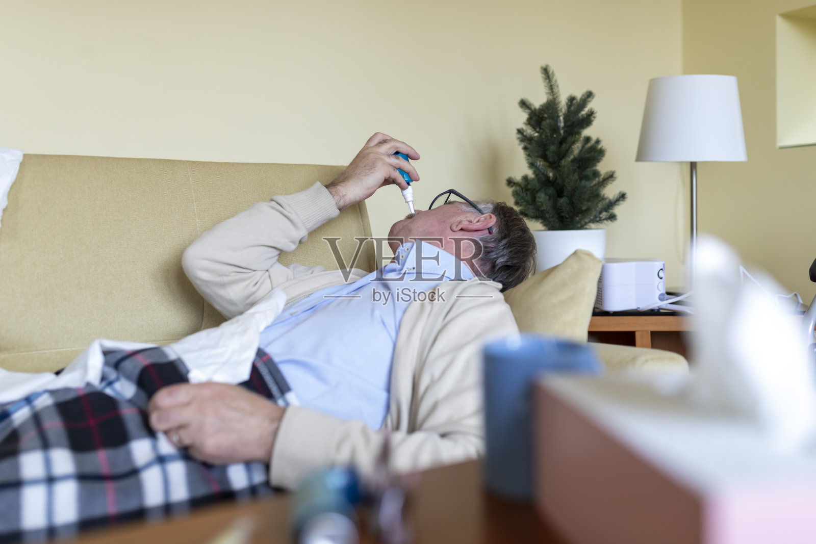 一位患有鼻炎的老人正在使用喷鼻剂。照片摄影图片