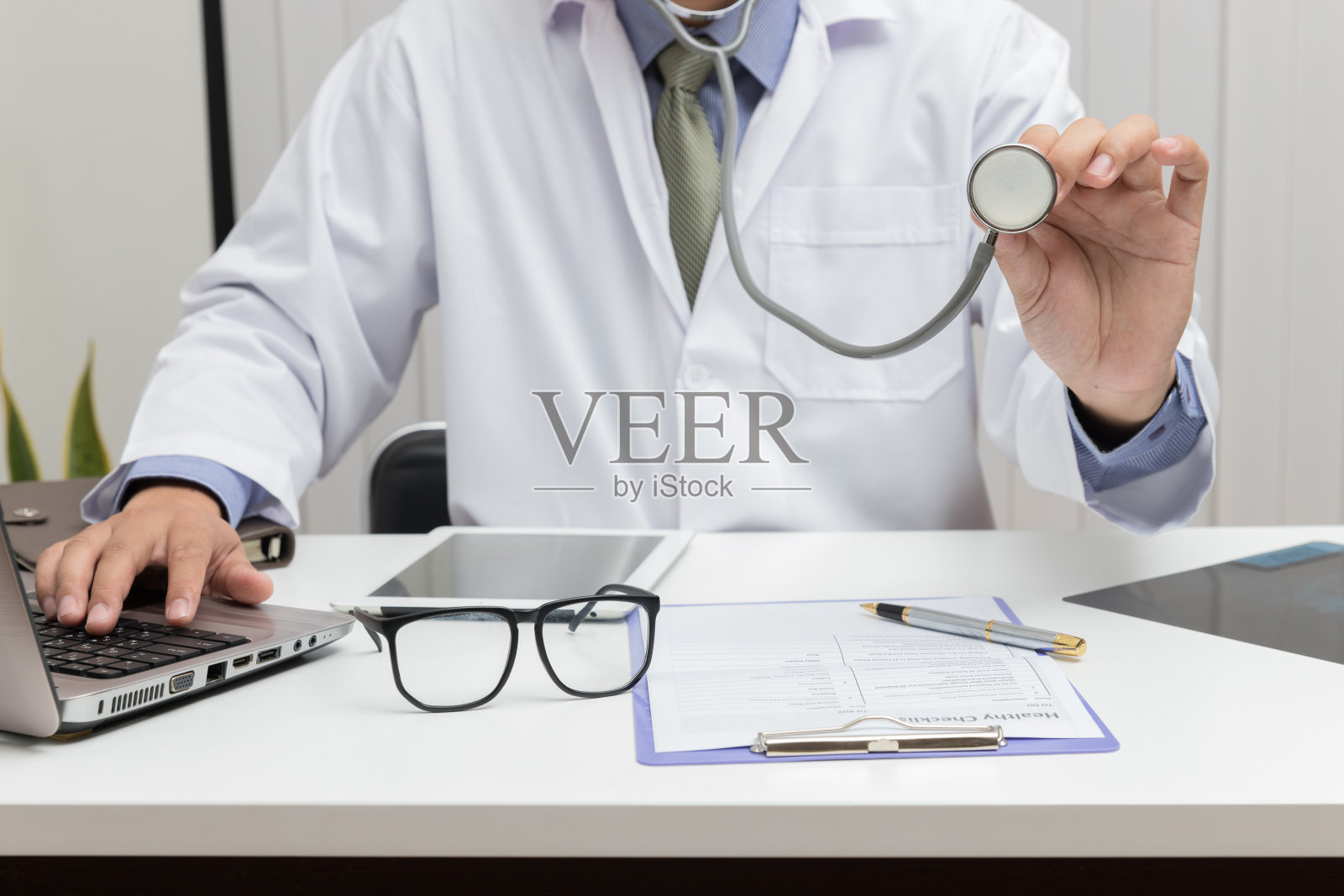 在医院医务室工作的带听诊器的男医生照片摄影图片