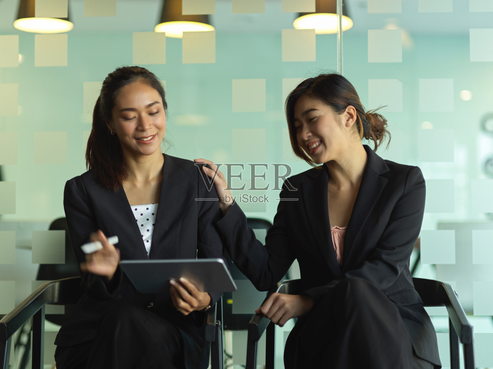 两个女商人在办公室里用数码平板电脑工作时交谈照片摄影图片