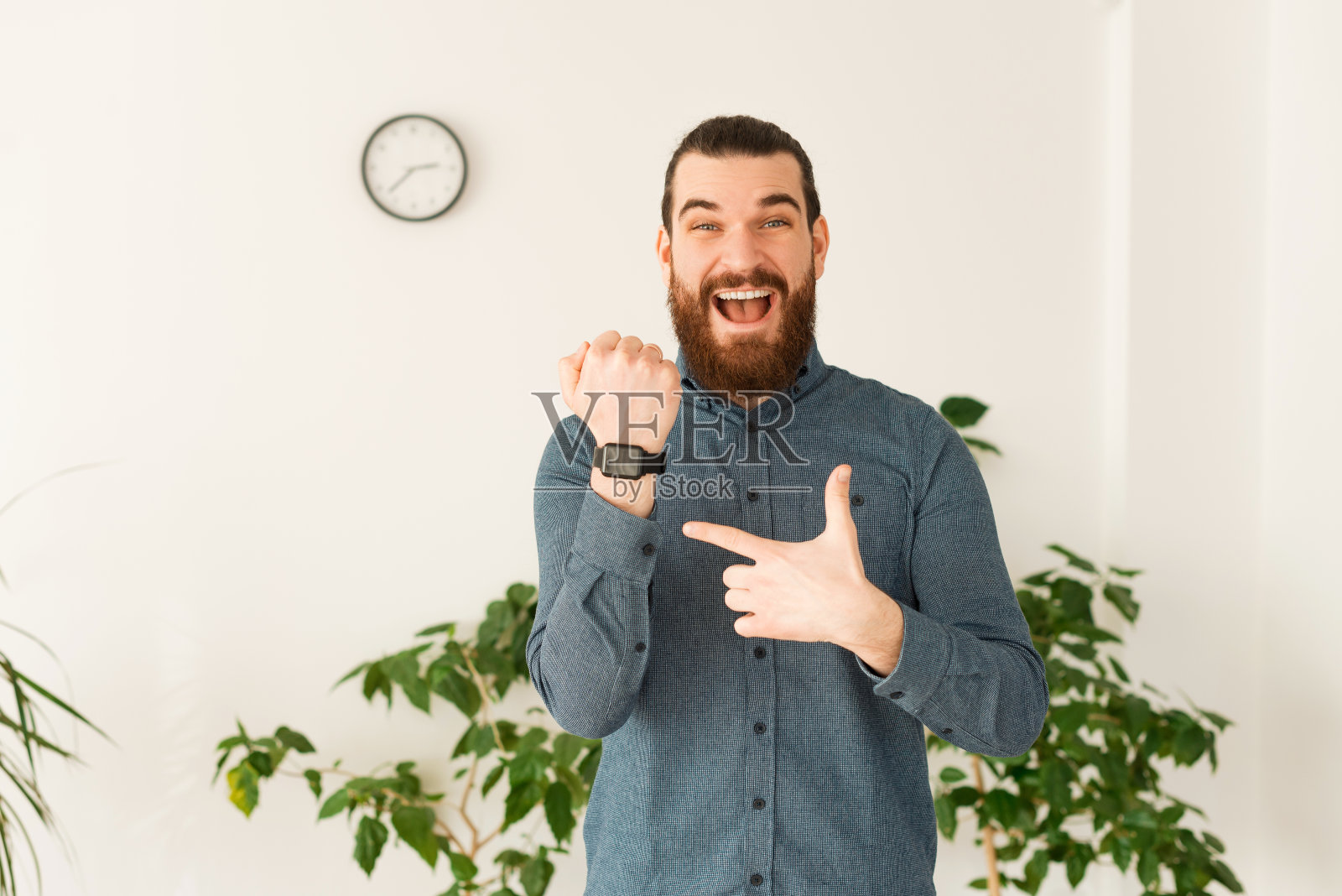 一幅惊讶的男人在办公室指着智能手表的肖像照片摄影图片