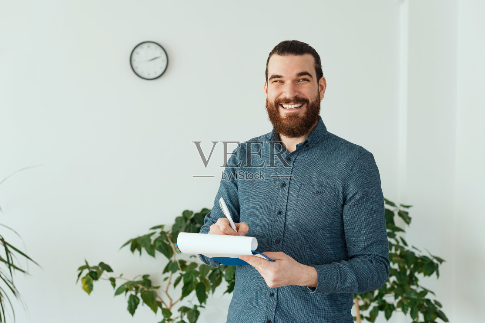 微笑的办公室职员看着相机和拿着纸和笔的照片照片摄影图片