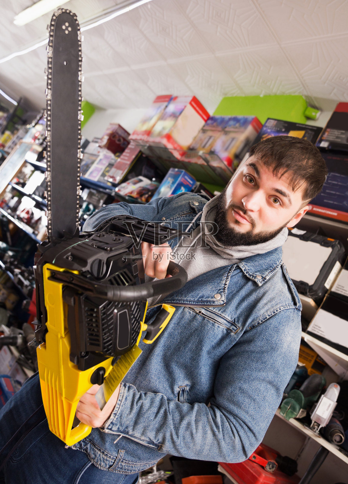 男站在工具店新链锯照片摄影图片
