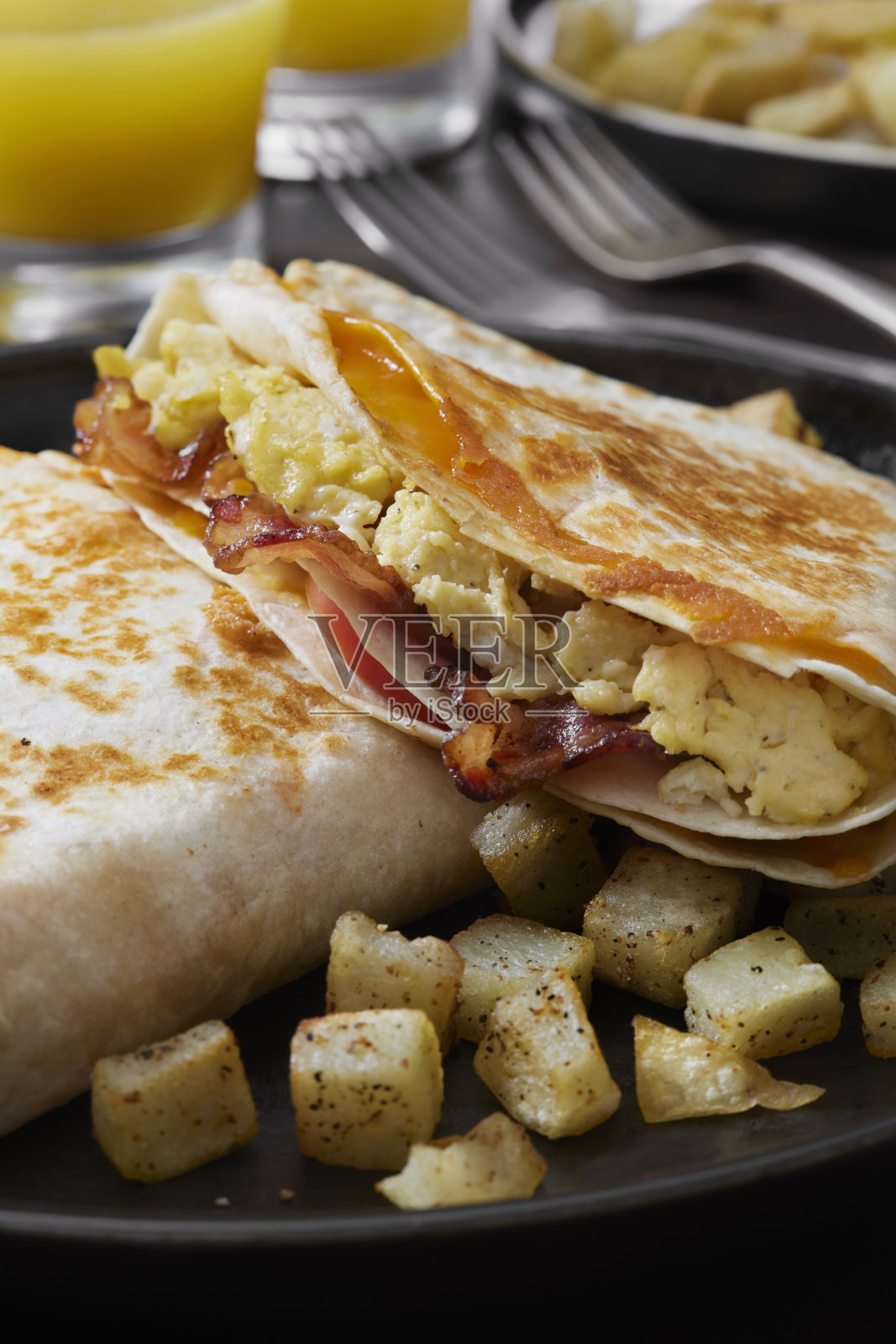 折叠早餐玉米饼，炒鸡蛋，培根，番茄和奶酪照片摄影图片