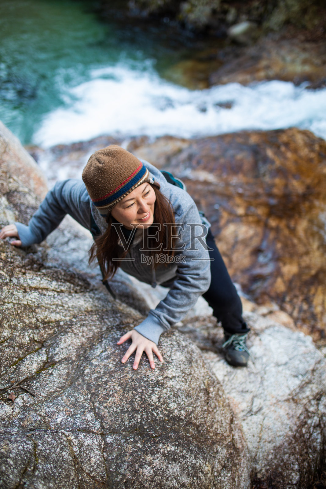 一名妇女在汹涌的水面上攀登悬崖照片摄影图片