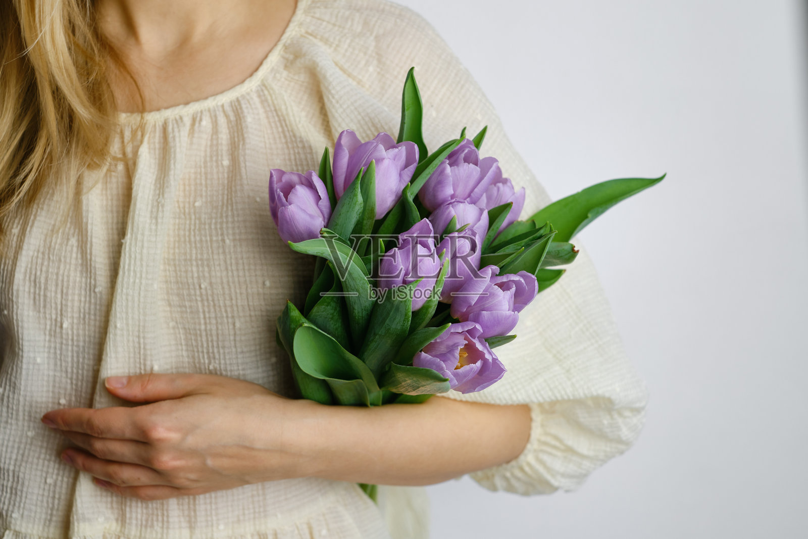 快乐的女人手里拿着紫色的郁金香。卖花的女孩收集了一束花。美丽的薰衣草花。花花瓣。庆祝节日的礼物，春天的心情。来自爱人的浪漫惊喜照片摄影图片