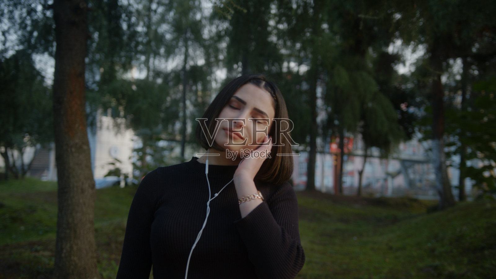 微笑的年轻美丽的女人戴着耳机听音乐和跳舞沿着公园的慢动作照片摄影图片