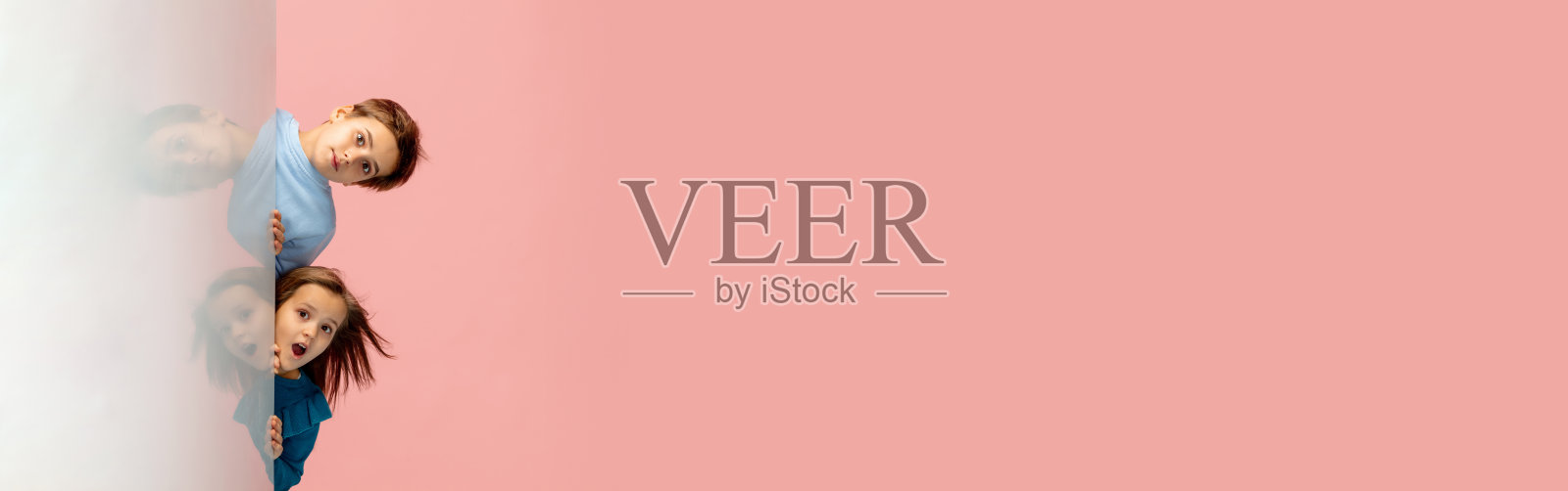 快乐的孩子隔离在珊瑚粉红色的工作室背景。看起来开心，开朗，真诚。Copyspace。童年，教育，情感概念照片摄影图片