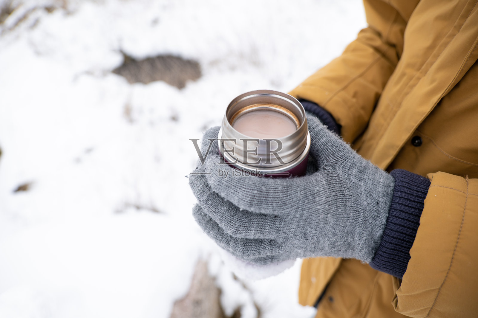 不认识的人拿着装有热巧克力的小热水瓶照片摄影图片