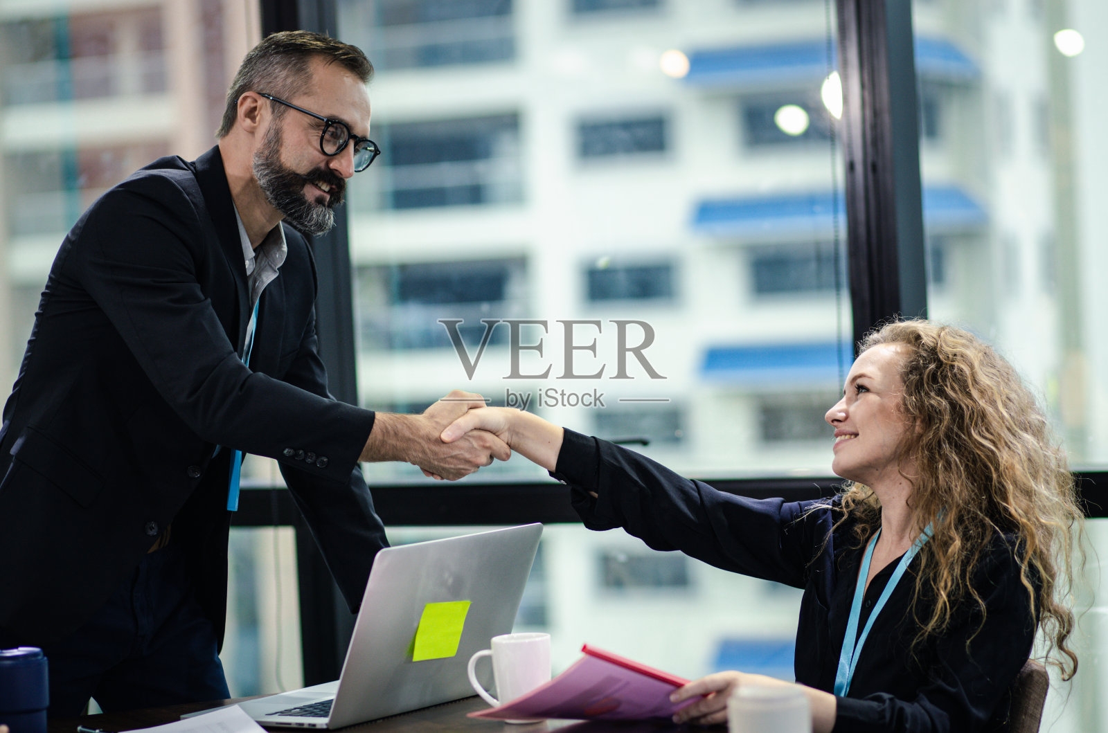 年轻的经理和新员工握手。商人在会议室握手，祝贺。照片摄影图片