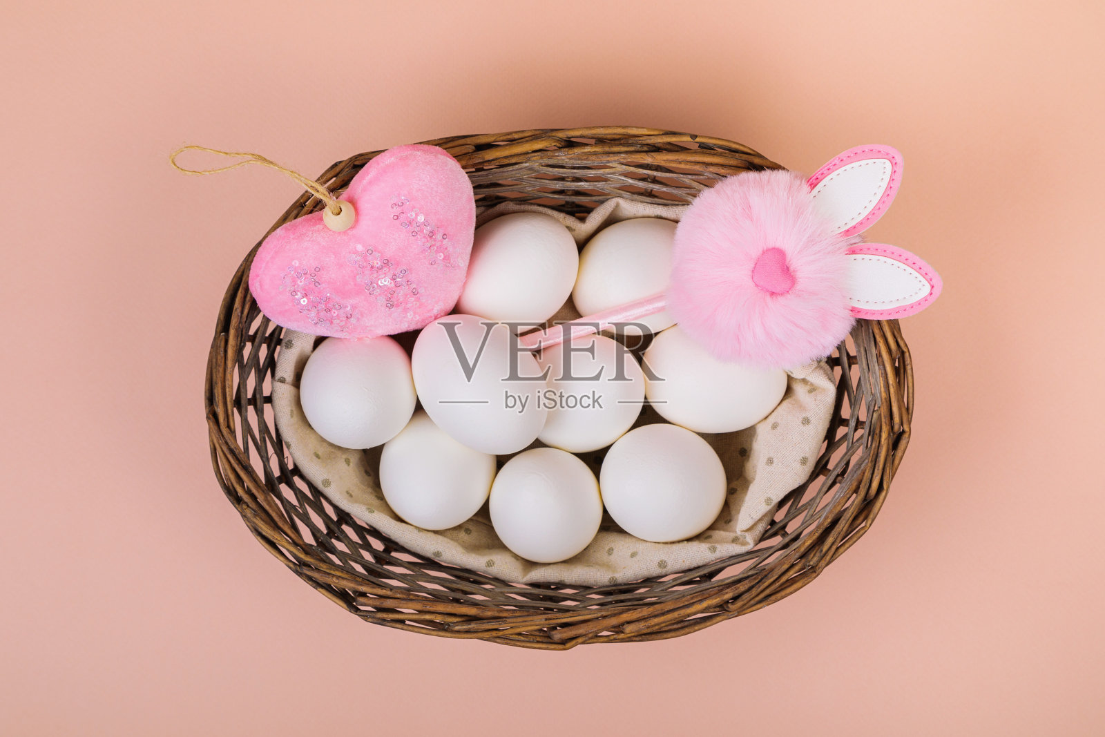 复活节。白色的鸡蛋放在篮子里，以统一的粉红色为背景。文本。照片摄影图片