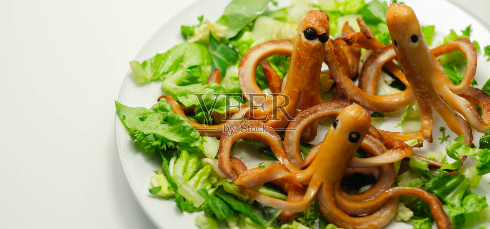 为孩子准备的创意餐，章鱼形状的炸香肠配上新鲜的宝石生菜照片摄影图片
