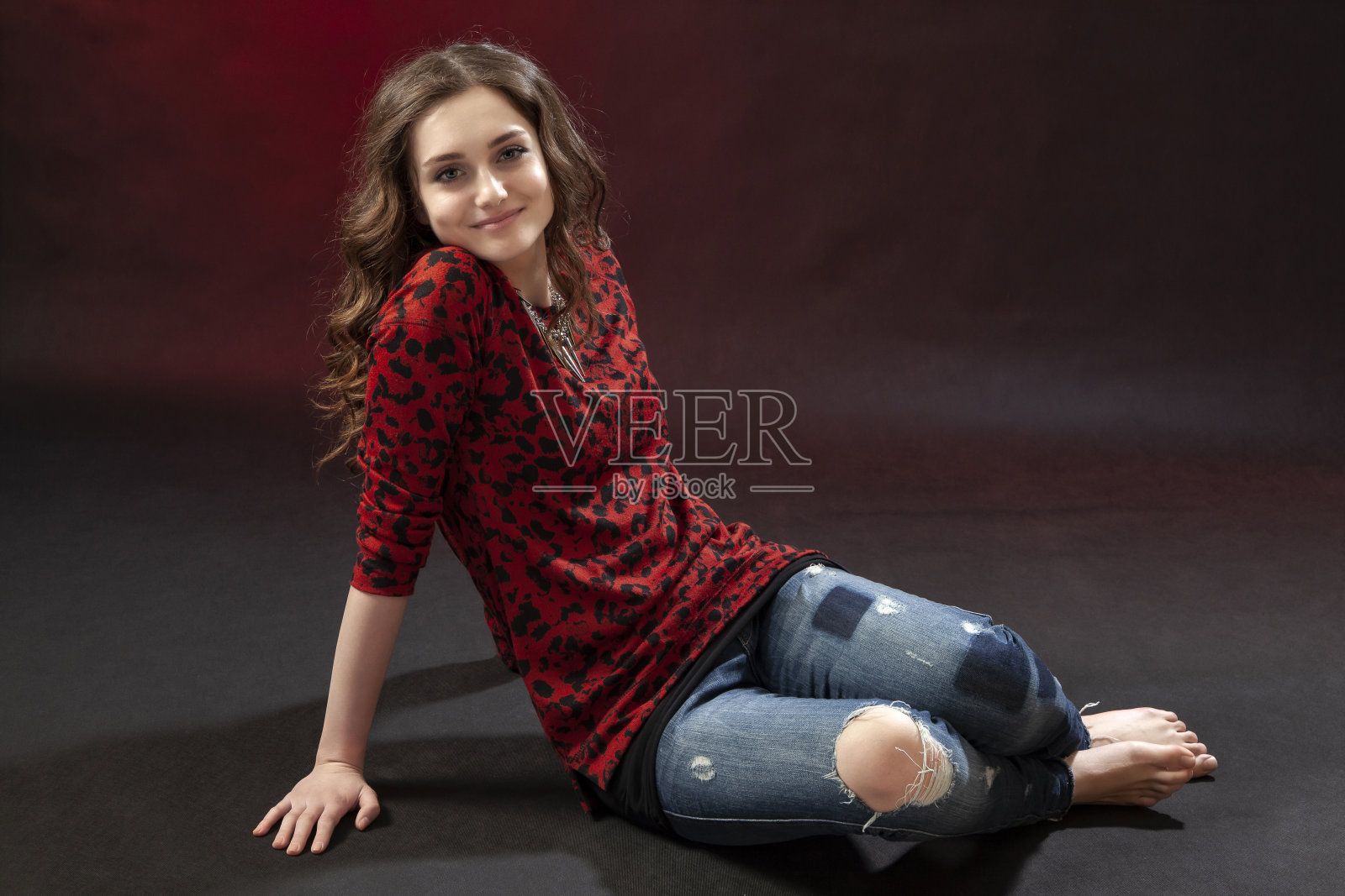 年轻女子的肖像穿着破旧的牛仔裤和红色衬衫。照片摄影图片