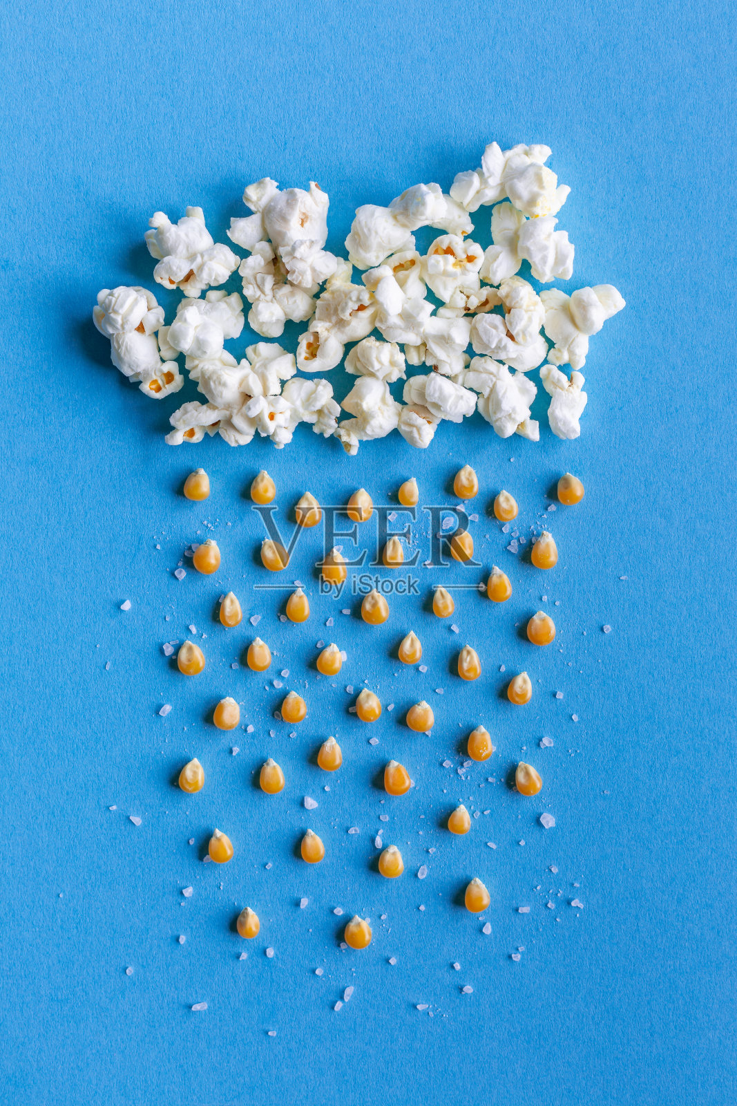 大的爆米花云与雨由玉米粒和盐在蓝色背景与复制空间照片摄影图片