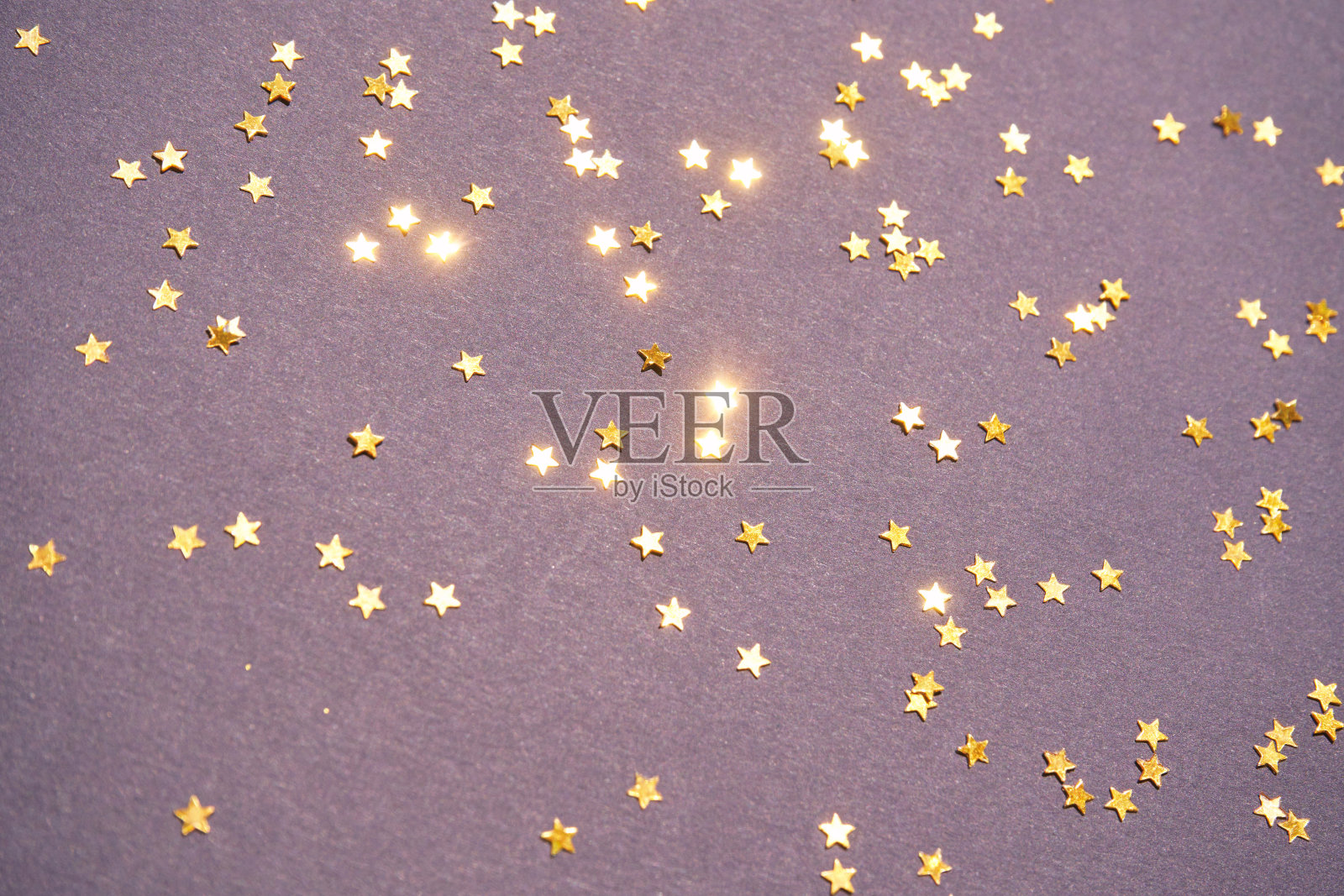 紫色背景上有金色的星星。黄色闪光背景。金色的纹理照片摄影图片
