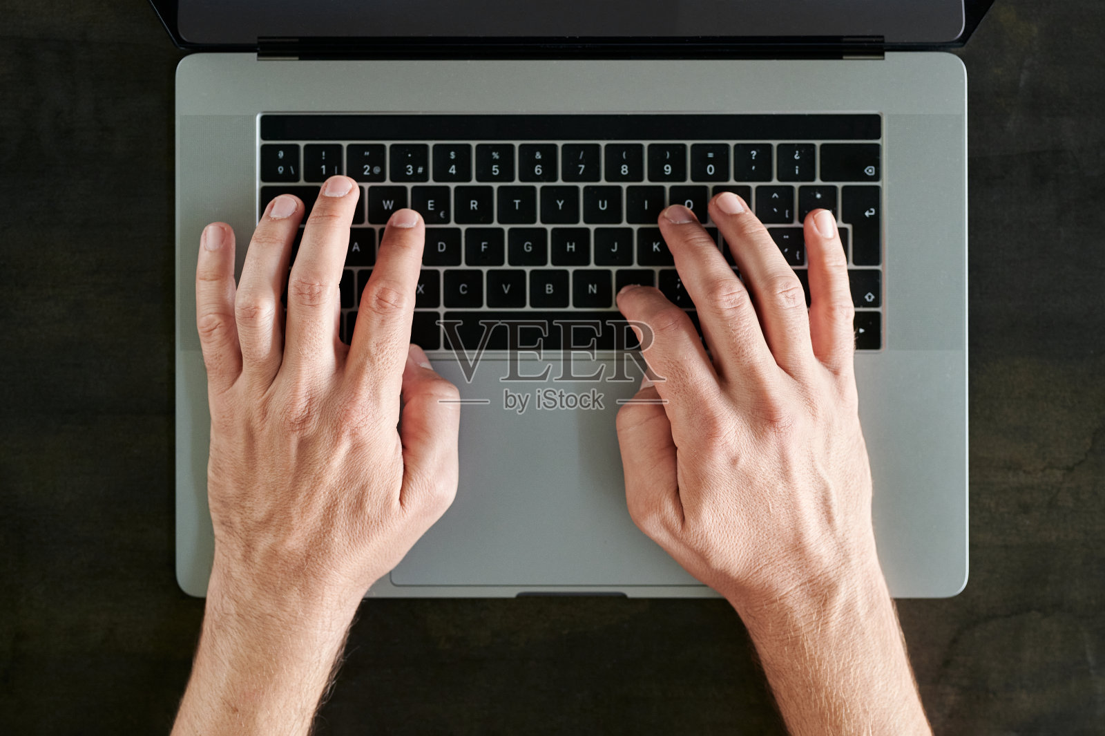 俯视图，一个男人的手打字与他的笔记本电脑在一个黑色的木桌照片摄影图片