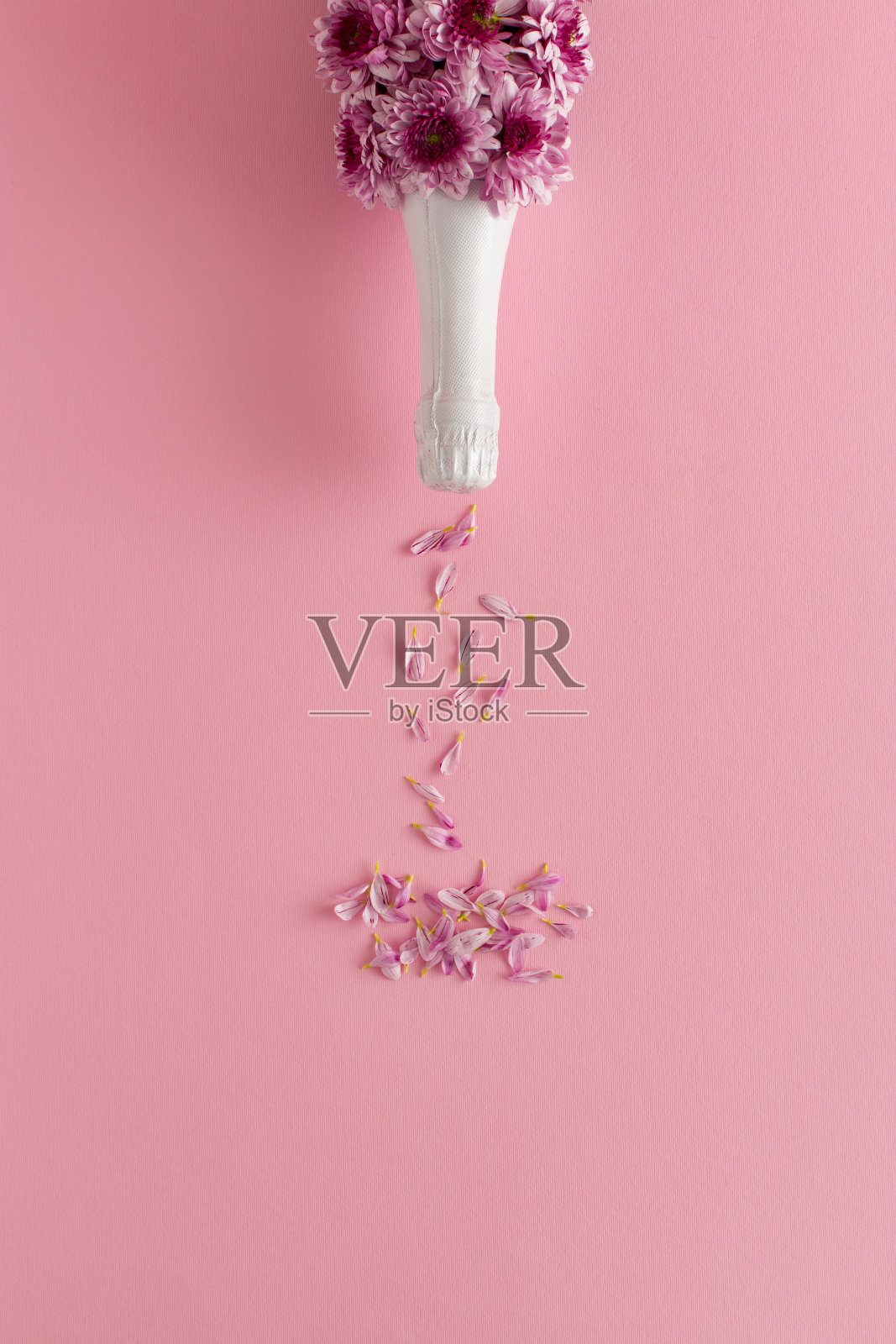 这是一个创意的爱情概念，以粉红色的背景为背景，用鲜花和花瓣制成的一瓶香槟。情人节或者女人节的点子照片摄影图片