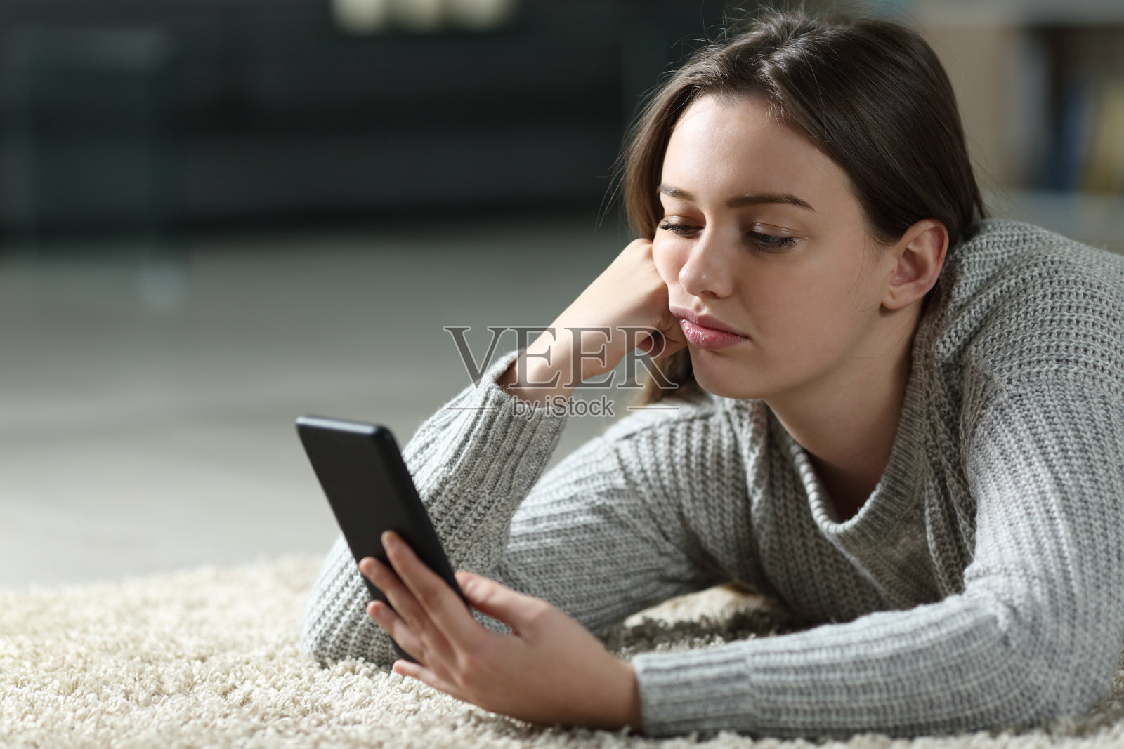 无聊的青少年在家里查看智能手机照片摄影图片