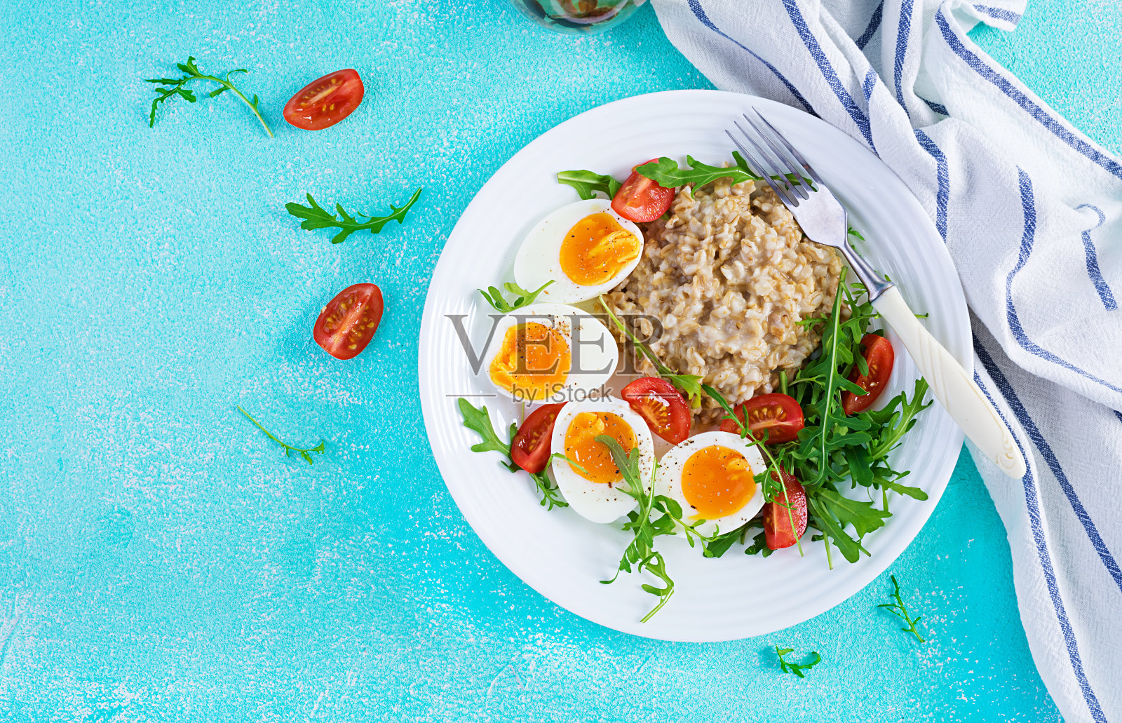 早餐燕麦粥配煮鸡蛋，樱桃番茄和芝麻菜。健康平衡的食物。顶部视图，上面，复制空间照片摄影图片