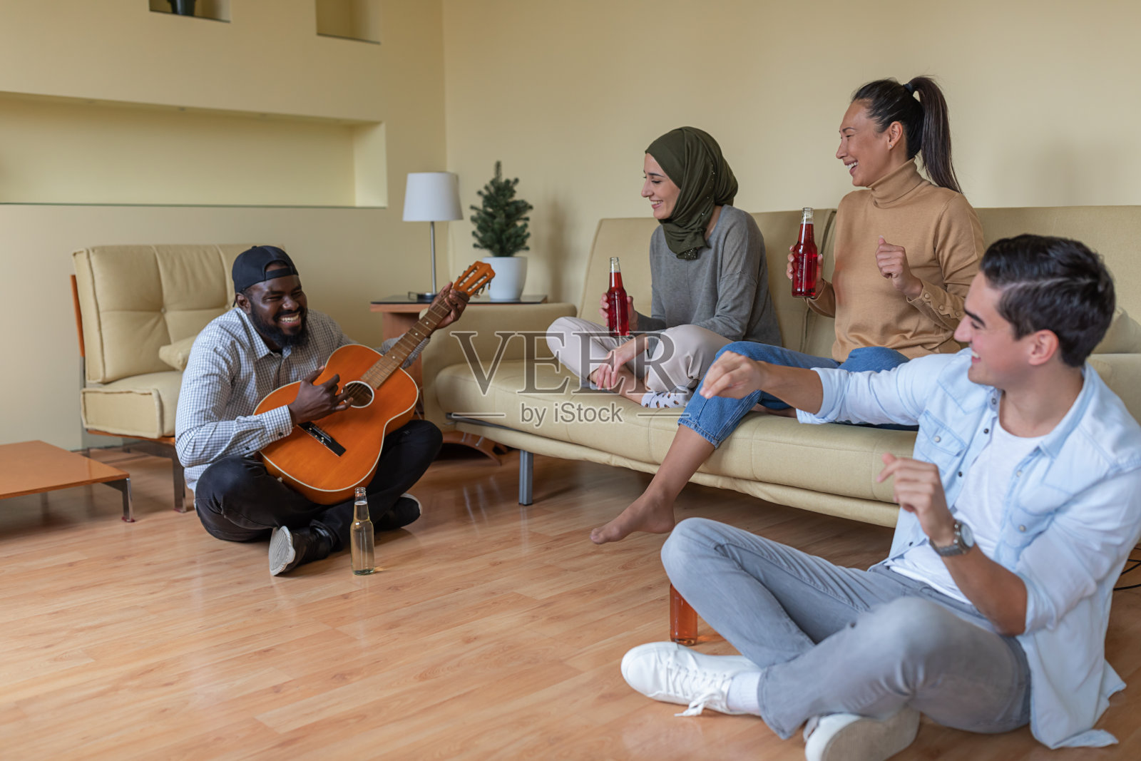 一群多元文化的朋友在家中弹吉他喝酒，玩得很开心照片摄影图片