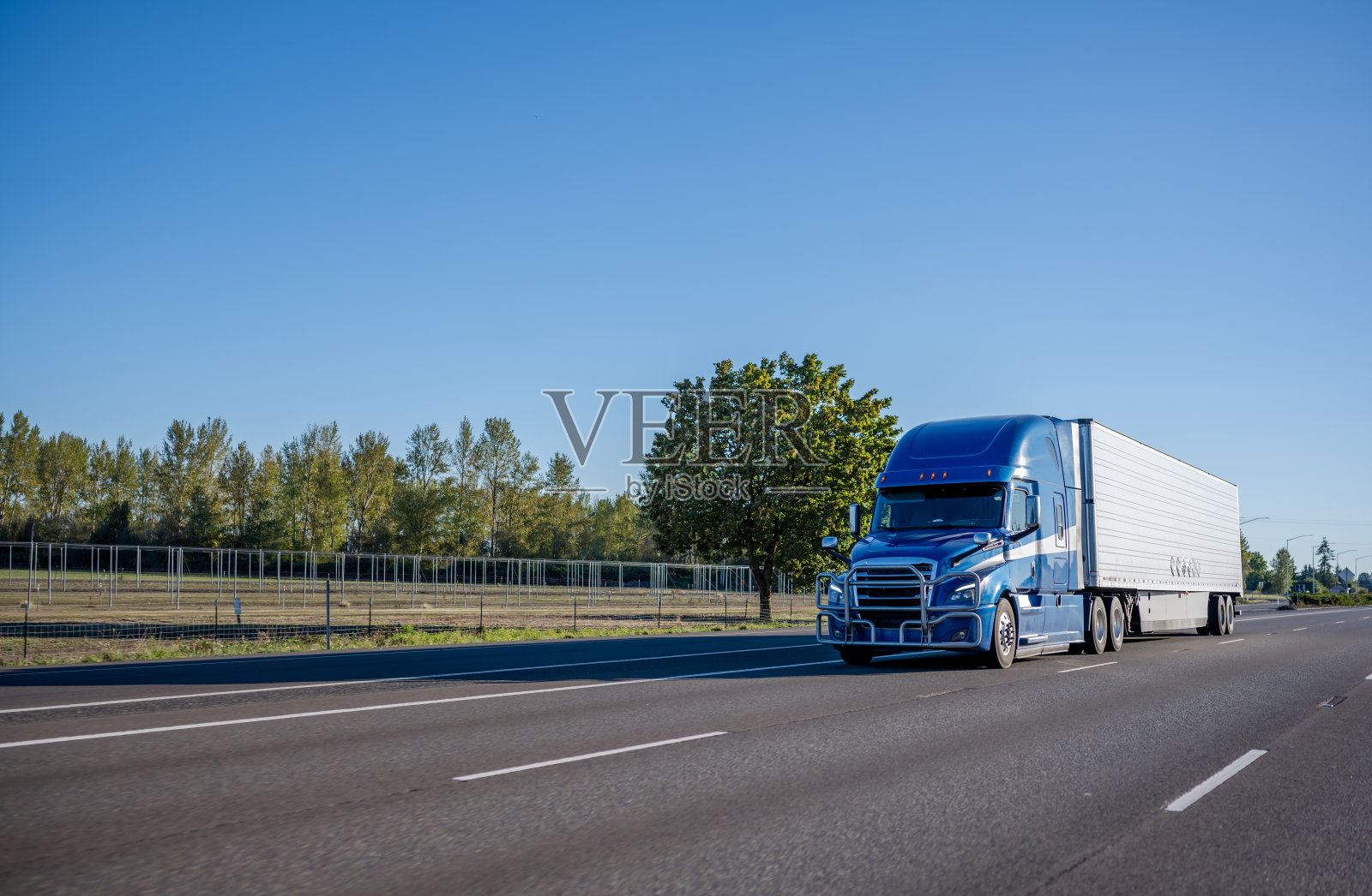 大卡车蓝色半挂车与管道格栅保护运输货物在冰箱半挂车行驶在宽多线直公路照片摄影图片