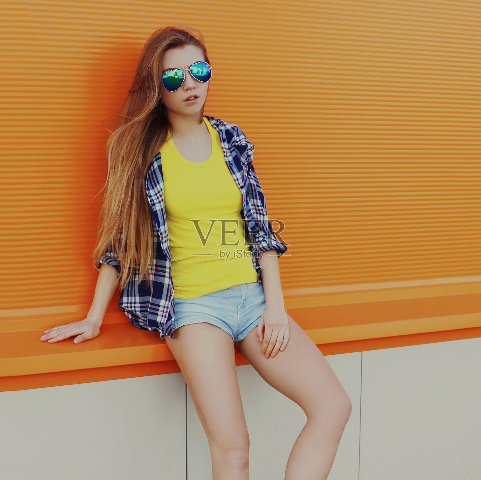 年轻女子的肖像与长发穿着一件衬衫在一个橙色的背景照片摄影图片