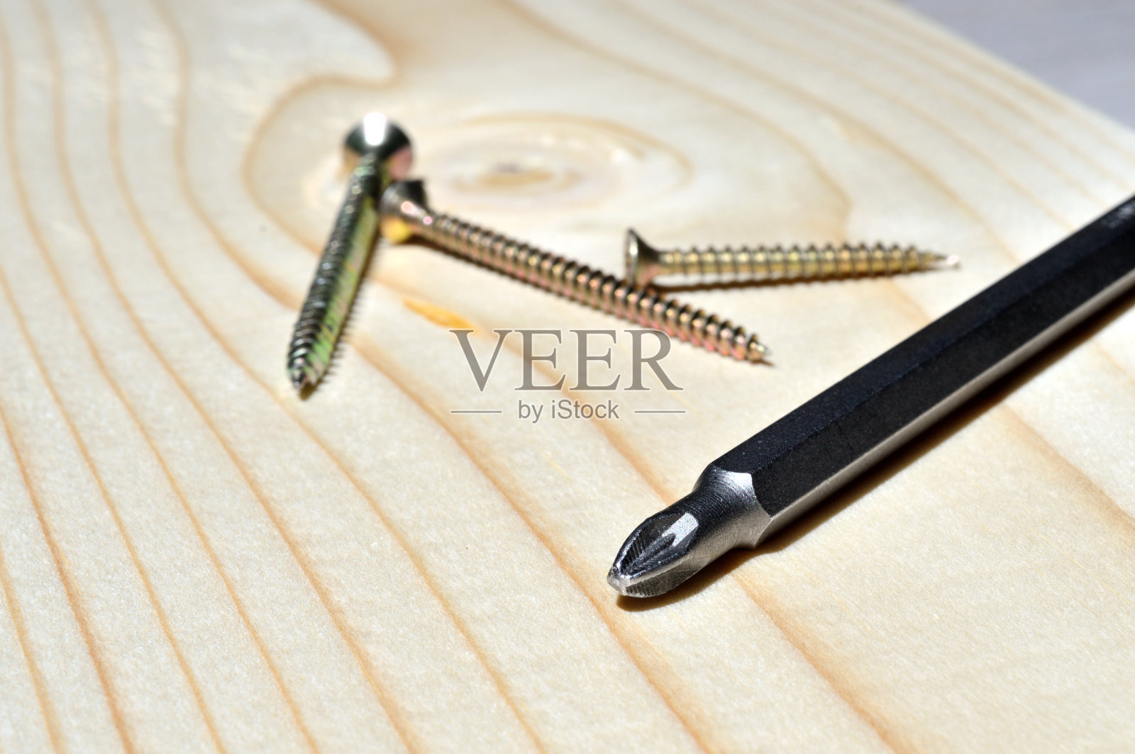 一块木头上放着一个螺丝刀和一些自攻螺钉。特写镜头。照片摄影图片