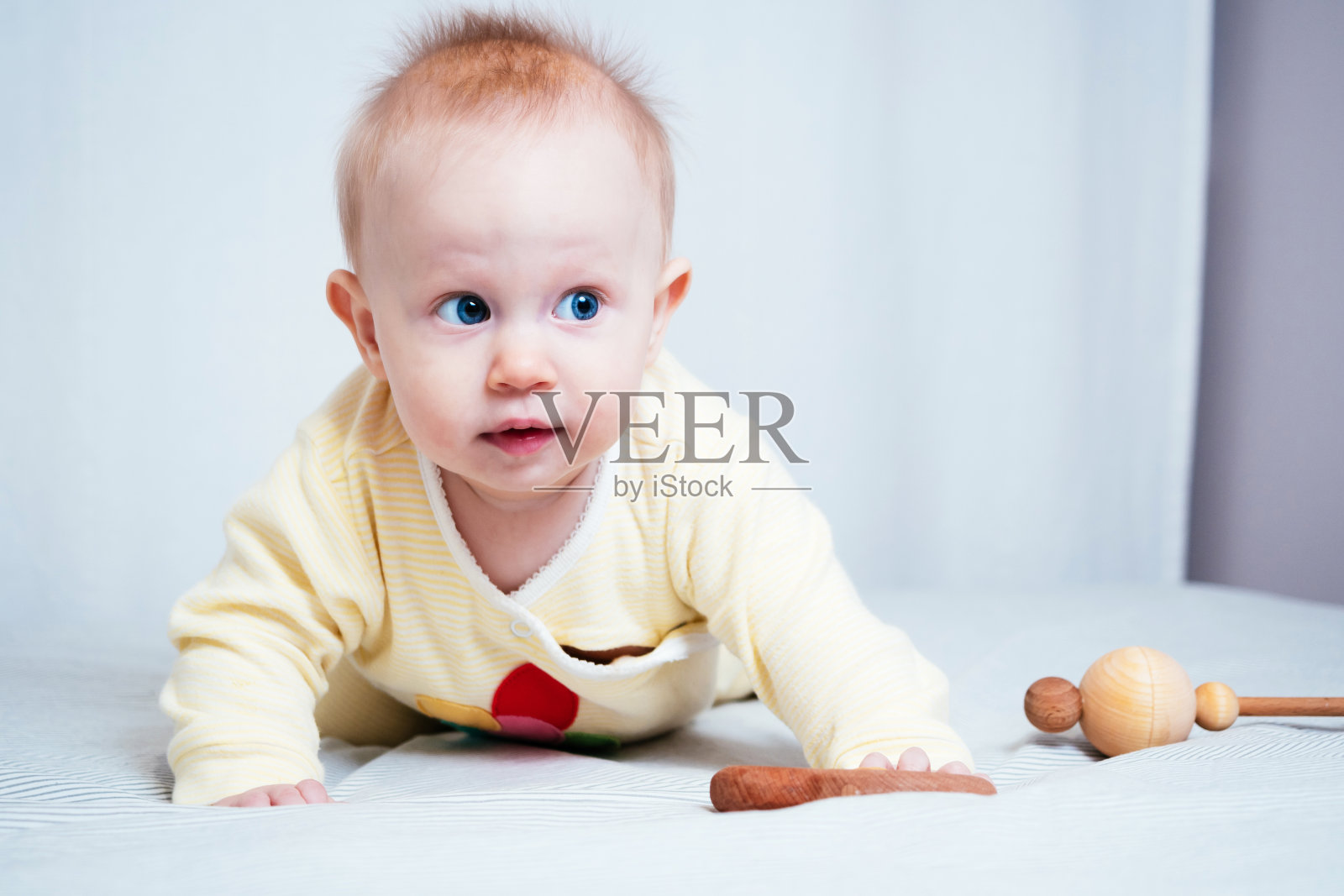 一个可爱的7个月大的蓝眼睛女孩的肖像。一个孩子在明亮的房间里玩木制玩具。由天然材料制成的环保儿童玩具照片摄影图片