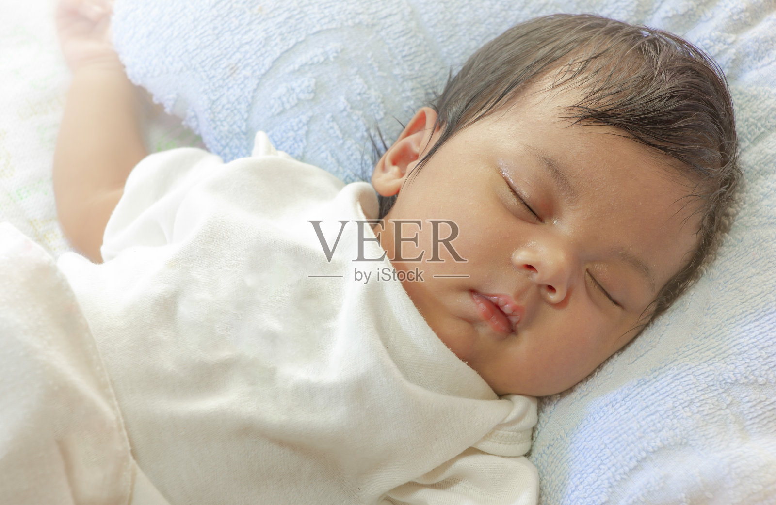 新生的亚洲女婴。刚出生的婴儿在阳光下睡在床上。照片摄影图片