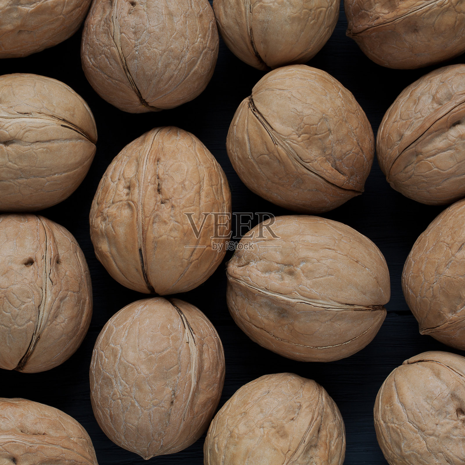 整颗带壳的核桃平躺在黑色的背景上照片摄影图片