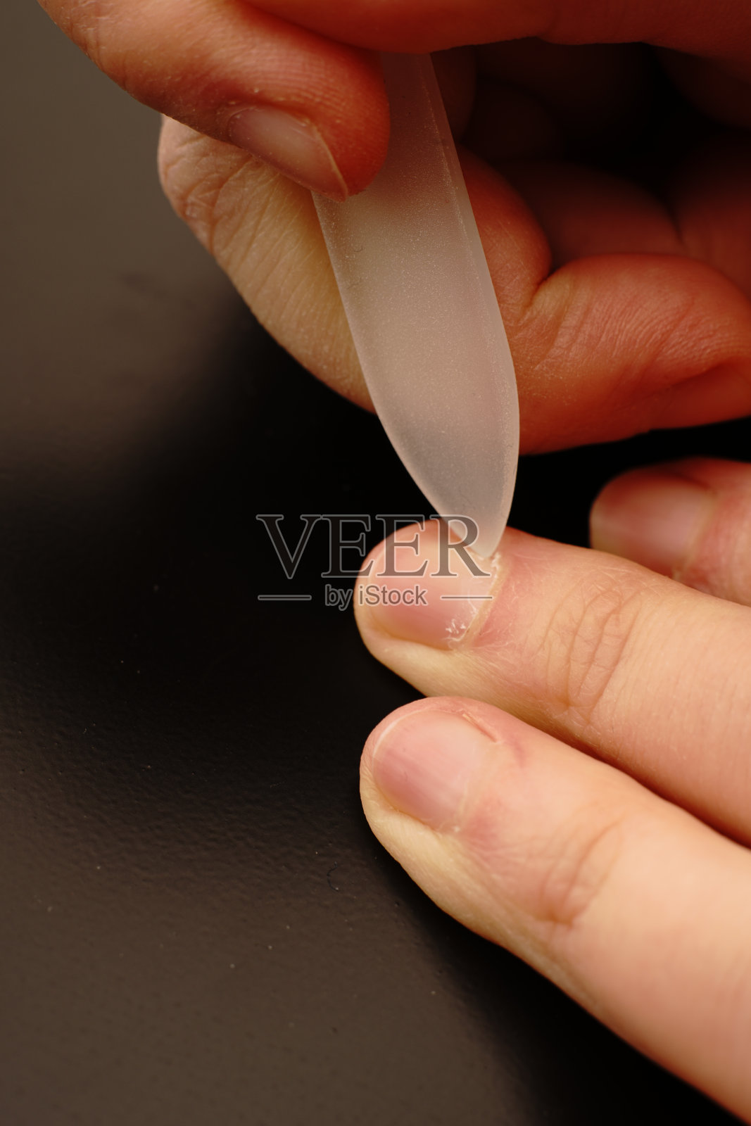 女人的手在黑色的背景上清洁她们的指甲。手护理。照片摄影图片