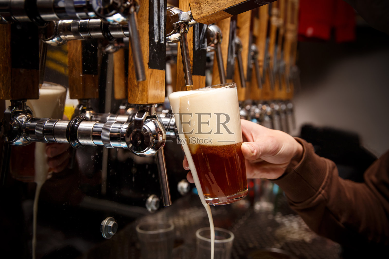 调酒师的手从水龙头里倒出红酒。照片摄影图片