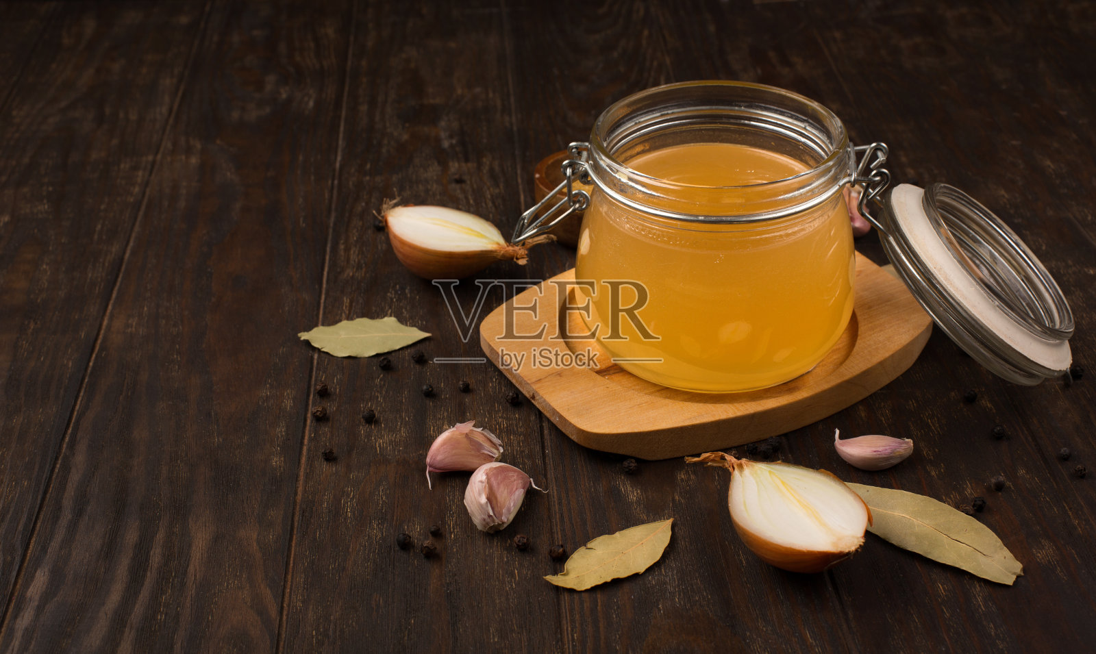 传统的自制牛肉骨汤和蔬菜在玻璃罐中，在黑暗的乡村木制背景。照片摄影图片