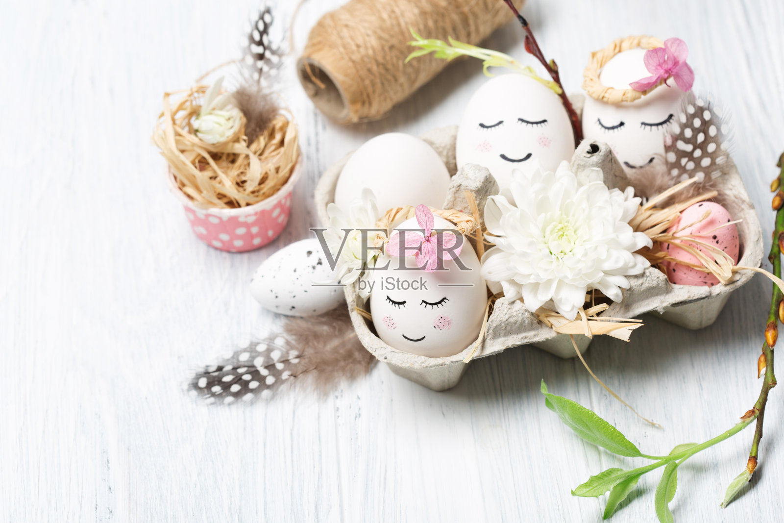 复活节的概念与可爱的手工制作的白色蛋，树枝，鹌鹑羽毛和春天的花在白色的木制背景。照片摄影图片