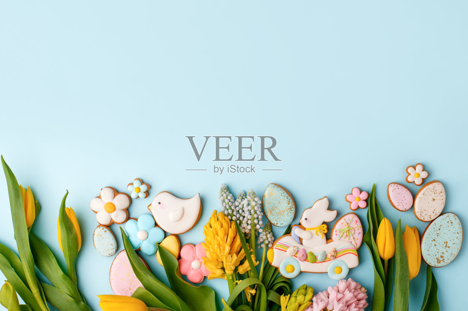 复活节快乐。五彩缤纷的复活节饼干，姜饼，季节性的花，郁金香在柔和的蓝色背景。复活节概念，拷贝空间，传单，横幅，优惠券，贺卡，邀请照片摄影图片